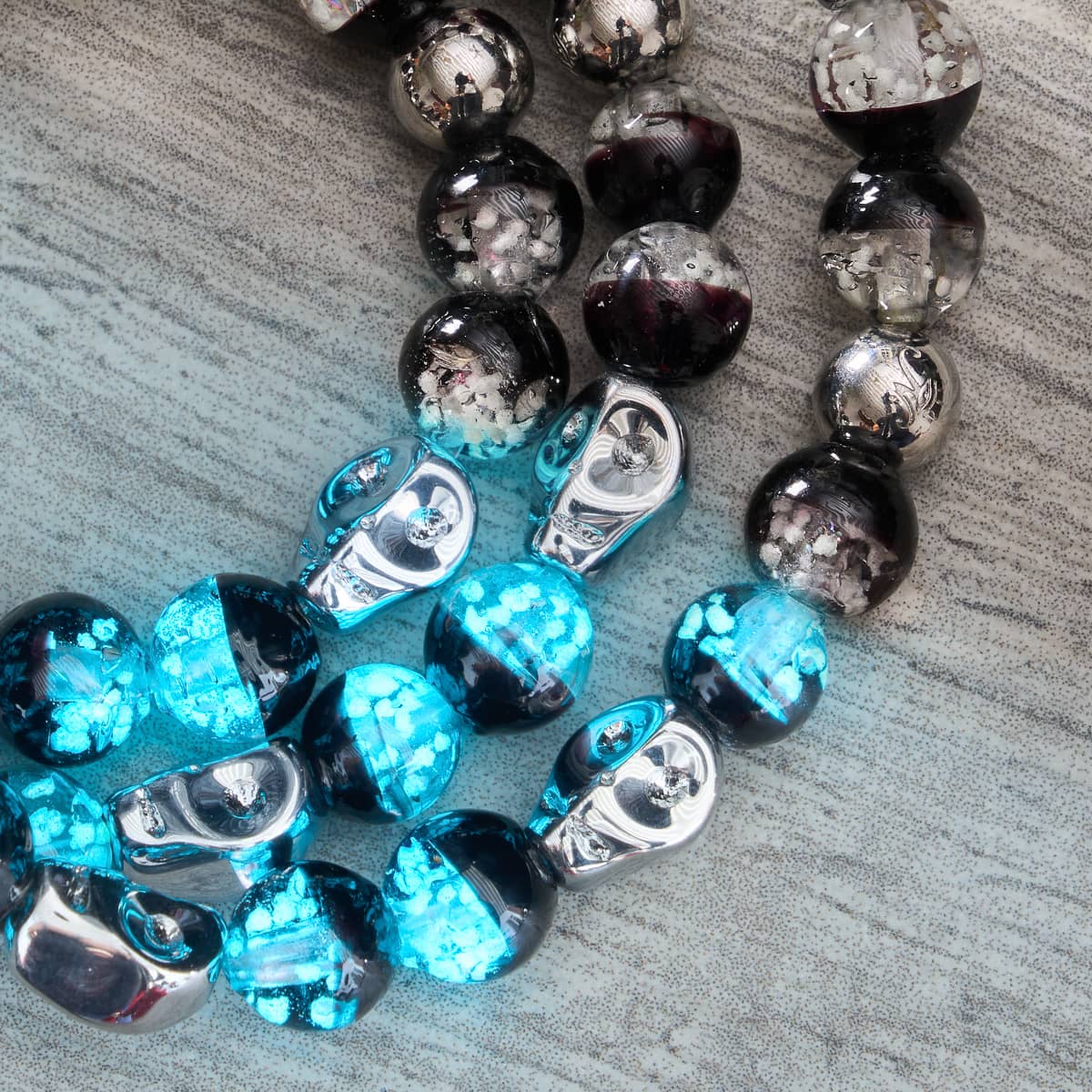 Nightfall Curse close-up of glowing turquoise Firefly Glass beads and polished .925 sterling silver skull beads by NOGU